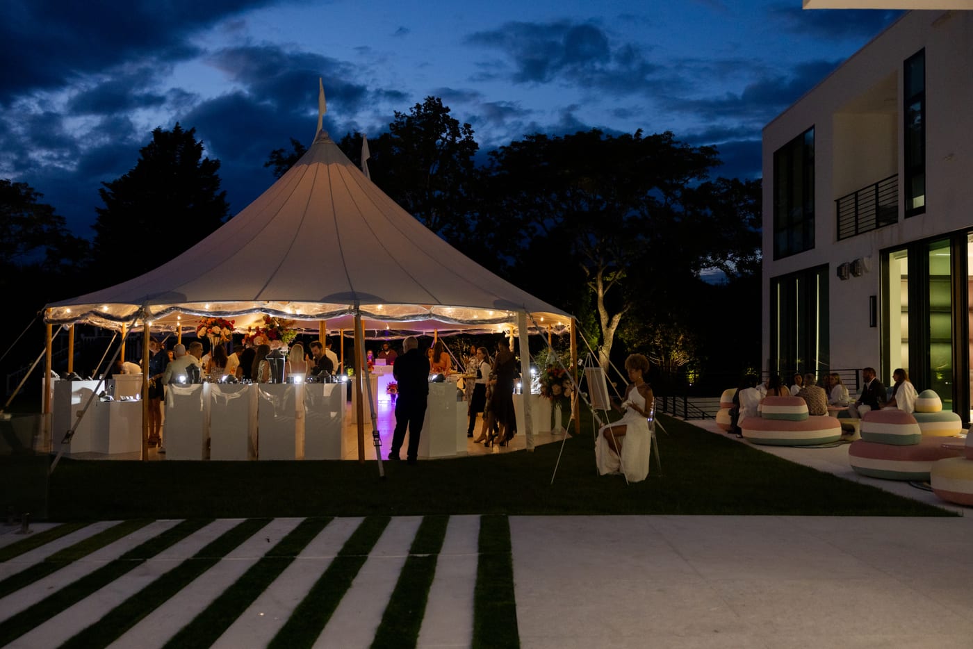 Sailcloth tent lit up at night during a Saks Fifth Avenue private estate event in Water Mill, New York